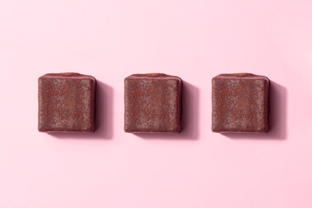 Handcrafted chocolate bonbons. Delicious dessert banner on a pink background with copyspace