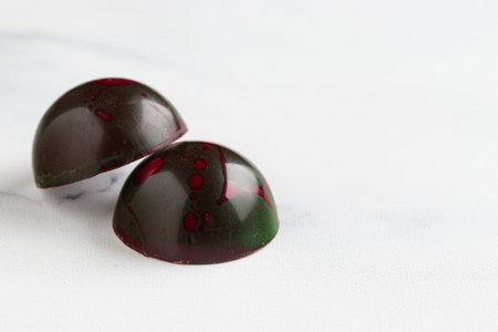 Pair of painted handcrafted chocolate bonbons. Delicious dessert on a white background with...