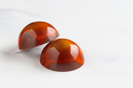 Pair of painted handcrafted chocolate bonbons. Delicious dessert on a white background with copyspaceの写真素材