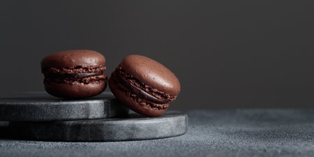 Chocolate eco handmade natural macaroons on dark background in the darkmood style. Horizontal banner top view with a copyspaceの写真素材