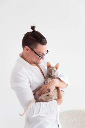 Joung man holding a cornish rex cat in his arms. portraitの写真素材