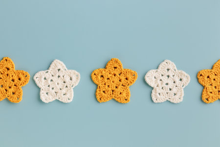 White and yellow crocheted stars row pattern on a blue backgroundの写真素材