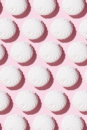 White zephyr on light pink table background in hard light. Pastel color. Closeup. Verticalの写真素材