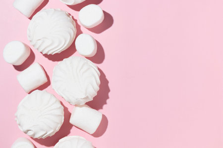 White marshmallows and zephyr on light pastel pink table. Banner with empty space for the text.の写真素材