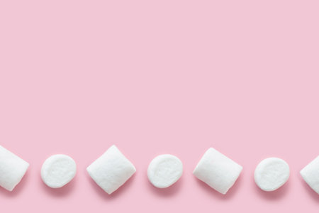 Row of white marshmallows pattern on light pink table background in hard light. Pastel color.の写真素材