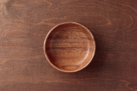 An empty wooden round bowl on the brown wooden table with copy space, empty utensilsの写真素材