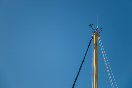 Wind indicator mounted on top of a sailboat mast. Wind direction and speed on a sailboat and blue skyの写真素材
