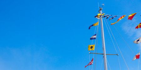 International maritime signal flags on a flagpole and masts on a sailing ship with a blue sky in the...