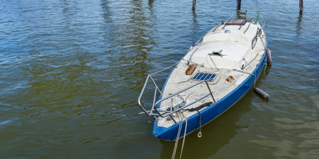 Close up of an old, dirty, crushed neglected abandoned sailing boat in the sea, Damaged light blue...
