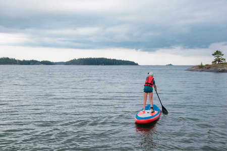 Little boy paddling on a paddle surfboard sup board in Baltic sea, Gulf of Finland, kids vacation,...