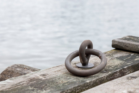 Mooring ring for boats in the port, old gray wooden pier in Baltic sea, Finlandの写真素材