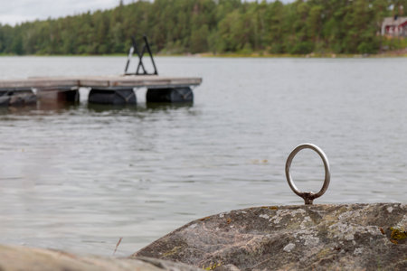 Mooring ring for boats in the stone, old gray wooden pier, pontoon on the background in the Gulf of Finland, Baltic seaの写真素材