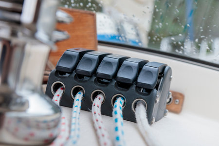 Sailing boat ropes at stoppers. Black line jammer. Yachting details.