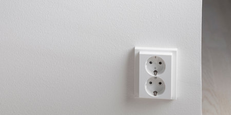 A close-up of a double electrical outlet mounted on a white wall. Mindful of electricity consumption...