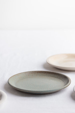 Empty rustic vintage plates dinnerware on a white tablecloth with copy space as a background for...