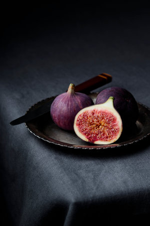 Fresh figs on a dark background, whole and a piece, ripe, delicious and sweet seasonal dessert with...