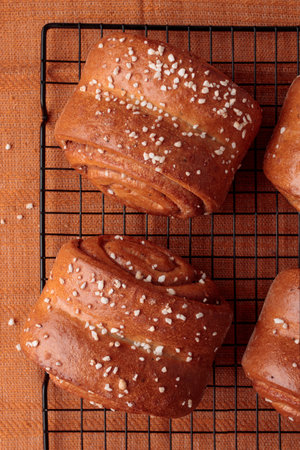 Korvapuusti, traditional Finnish cinnamon and cardamom rolls, fresh baked buns on the metal grid, sweet dessert Sweden and Finland, warm brown colorsの写真素材