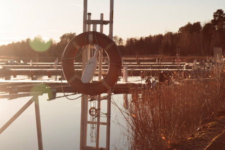SOS nautical emergency concept. Lifebuoy in a marina near the sea at autumn, with sun on the...