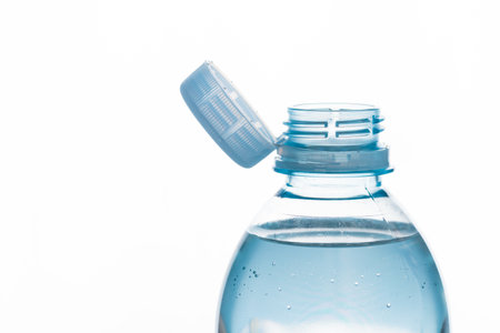 Close up of new cap attached to plastic bottle, connected to the neck of the bottle by solid tab...
