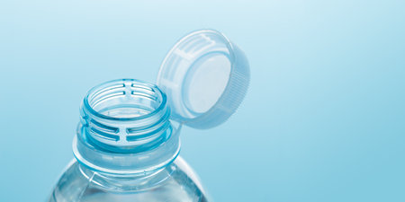 Close up of new cap attached to plastic bottle, connected to the neck of the bottle by solid tab...