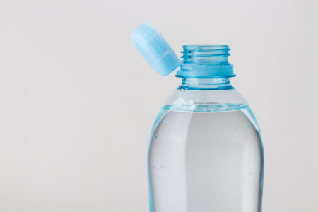 Close up of new cap attached to plastic bottle, connected to the neck of the bottle by solid tab attached to safety ring. They are intended to encourage recycling, as part of the fight against litterの写真素材
