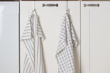 A minimalistic white kitchen cabinet beneath the sink holds a dish rag or towels, blending style with functionality and keeping essentials within easy reachの写真素材