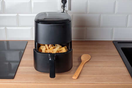 Trendy kitchen gadget air fryer machine cooking deep-fried potato. Lifestyle of new cooking, small countertop convection oven, deep fast frying oil free, more healthy way to cook deep-fried foodの写真素材