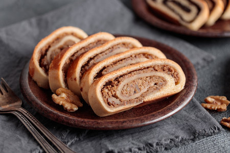 Home baked walnut roll, bejgli in slices, traditional Hungarian sweet bread stuffed with walnut filling. Eastern European Christmas and Easter nut roll made with ground walnuts. Closeup on the table. Horizontal side viewの写真素材