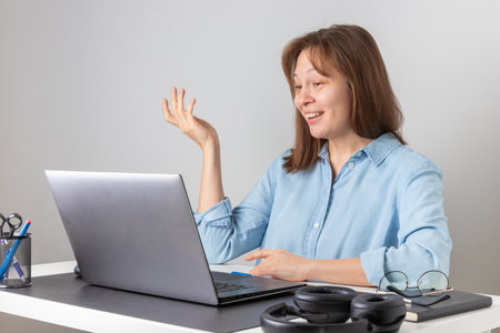 Happy young woman using laptop, watching webinar, studying online, looking at pc screen learning web classes or having virtual call meeting remote working from homeの写真素材