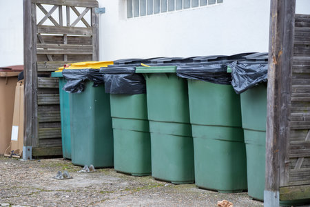 Different colored waste bins are neatly arranged along the side of a residential street. These containers for recycling and waste disposal. Paris, Franceの写真素材