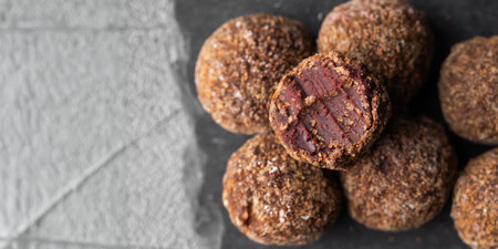Artisan chocolate truffle candies with berry and fruit filling on dark background, handmade or handcrafted bonbons, chocolatier or confectionary concept. Horizontal banner, copy spaceの写真素材