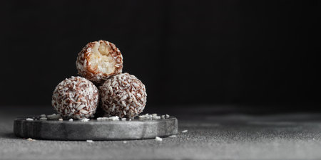 Artisan chocolate truffle candies with coconut filling on dark marble background from confectionary....