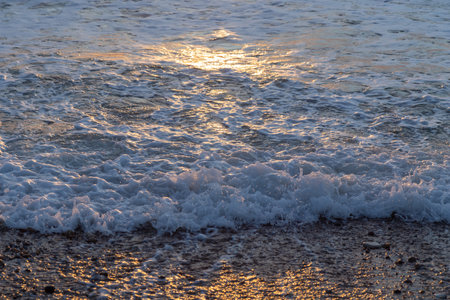 Abstract photo of surface water waves of sea or ocean at sunset time with golden light tone. Pattern for background.の写真素材