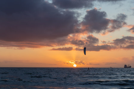 Sunset sky over the English Channel with a kiteboarder riding kiteboard silhouette. Active sport people and beauty in Nature concept image. La Manche, Franceの写真素材