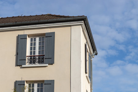 A sunny morning in the French town - a building's corner and French window with opened shutters, blue sky at the backgroundの写真素材