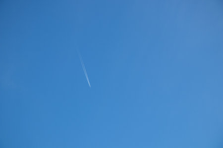 Jet plane aircraft with contrails cruising in the clear sky to the southの写真素材