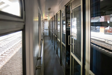 A corridor inside a passenger Second-class train carriage in Poland. Long and linear, with windows on one side and cabin doors on the other, it captures the classic atmosphere of rail travel in motionの写真素材