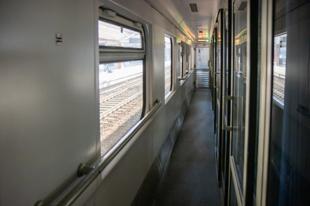 A corridor inside a passenger Second-class train carriage in Poland. Long and linear, with windows on one side and cabin doors on the other, it captures the classic atmosphere of rail travel in motionの写真素材