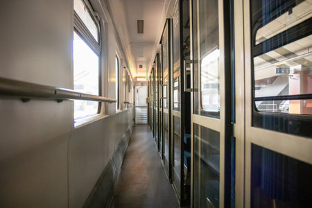 A corridor inside a passenger Second-class train carriage in Poland. Long and linear, with windows on one side and cabin doors on the other, it captures the classic atmosphere of rail travel in motionの写真素材