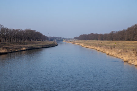 The Oder River flowing through the cityscape, bordered by green riverbanks. A harmonious blend of nature and city life with reflections on calm waterの写真素材