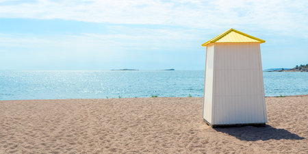 Sunny sandy beach in Hanko, Finland, with colorful iconic changing cabin, hut, booth, a cheerful Finnish Riviera vibe and relaxing seaside summer resort atmosphere with a sea view, bannerの写真素材