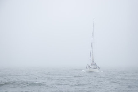 Serene nautical scene of sailing boat moves silently through thick fog in the Gulf of Finland,...