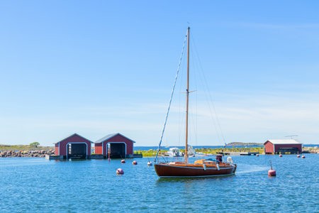 Small sail boat is mooring to Finnish harbor in calm waters. The rustic maritime lifestyle, close...