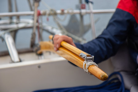 Skilled young man steering a sailboat with wooden tiller on the open waters of the Gulf of Finland....