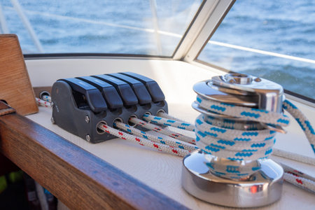 Sailboat winch on a sailing boat and ropes at stoppers, line jammer. Yachting details of rigging on...