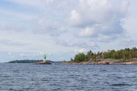 Marine channel marker on coastal rocks with green top, indicating the edge of the channel. Coastal navigation aid in Baltic sea, highlighting safety, marine guidance, and rocky shorelineの写真素材