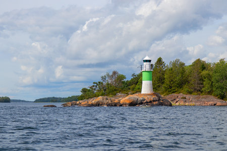 Marine channel marker on coastal rocks with green top, indicating the edge of the channel. Coastal navigation aid in Baltic sea, highlighting safety, marine guidance, and rocky shorelineの写真素材