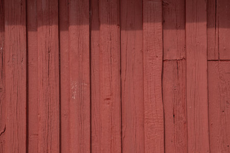 Close-up texture of red painted timber wall, reflecting ecological Nordic tradition of sustainable housing craftsmanship, and simple rural architectureの写真素材