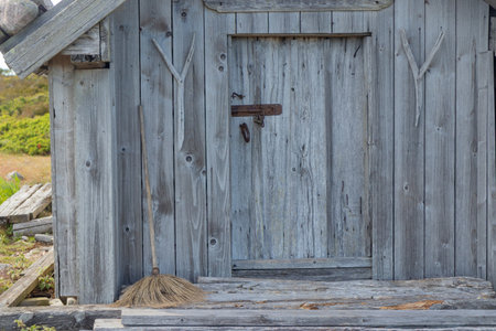 Metal latch on weathered gray wooden door. Natural timber aged by time, highlighting texture, patina, and rustic Nordic craftsmanship in rural architectureの写真素材