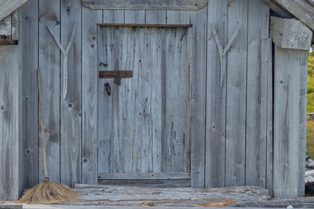 Metal latch on weathered gray wooden door. Natural timber aged by time, highlighting texture, patina, and rustic Nordic craftsmanship in rural architectureの写真素材